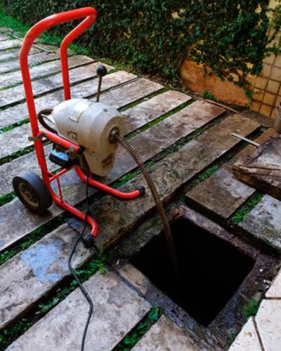 Serviço de limpeza de esgoto - trabalhador desentope um ralo com hidrojateamento.